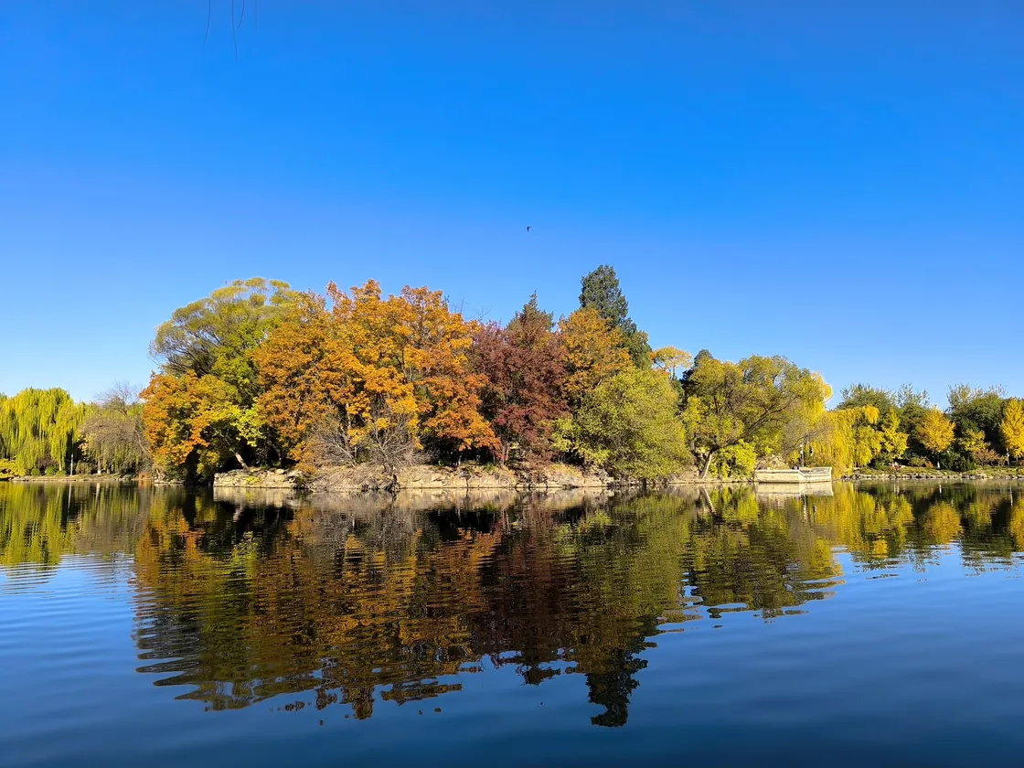 Autumn trees reflected in Weiming Lake on a quiet university campus